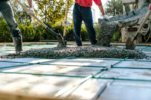 Betonarbeiten im Freien. Arbeiter verteilen frischen Beton mit Schaufeln.