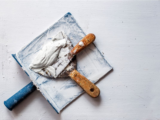 Maurerkelle auf weißem Betonboden.